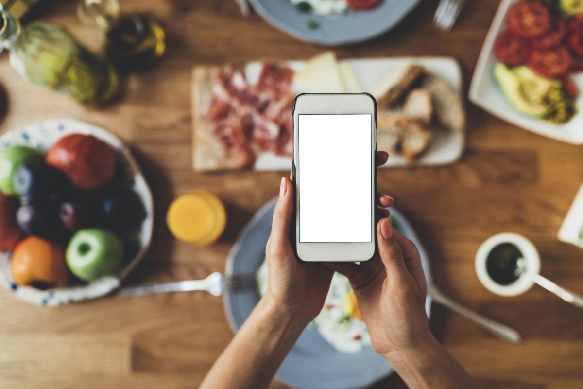 A mobile phone with table full of food in the background