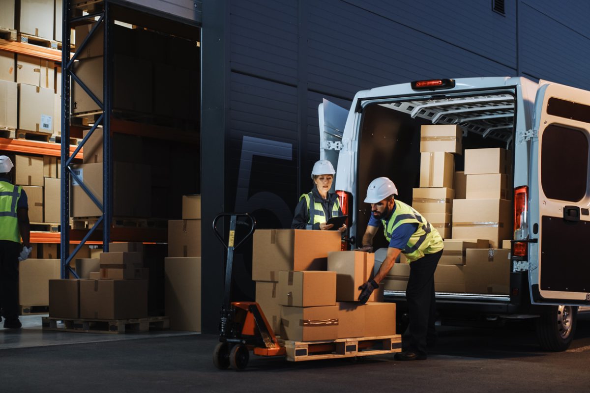 Outside of Logistics Retail Warehouse With Inventory Manager Using Tablet Computer, talking to Worker Loading Delivery Truck with Cardboard Boxes, Online Orders, Food and Medicine Supply, E-Commerce
