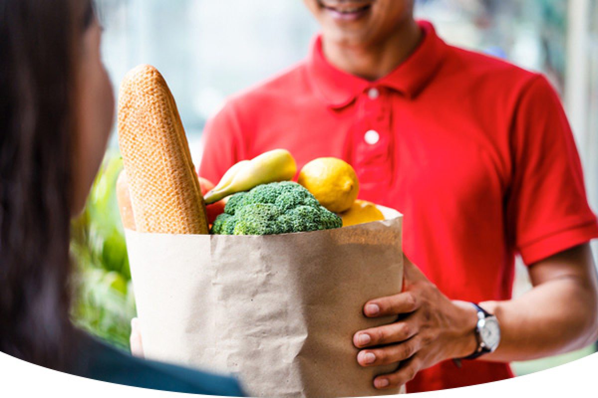 man handing over grocery bag to woman
